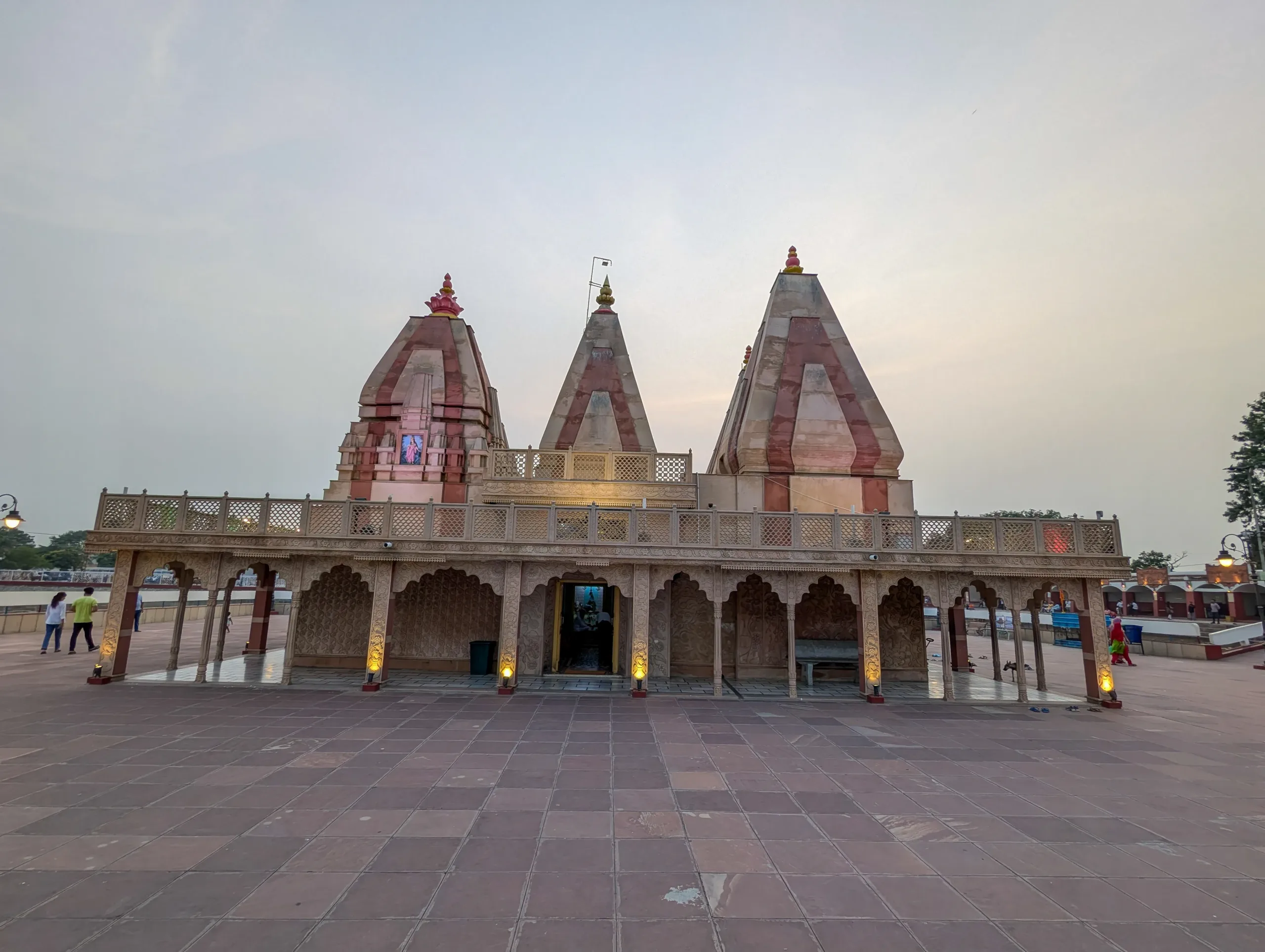 Evening front view of Sarveshwar Mahadev Temple at Brahma Sarovar in Kurukshetra with lit arches and striped pink shikharas
