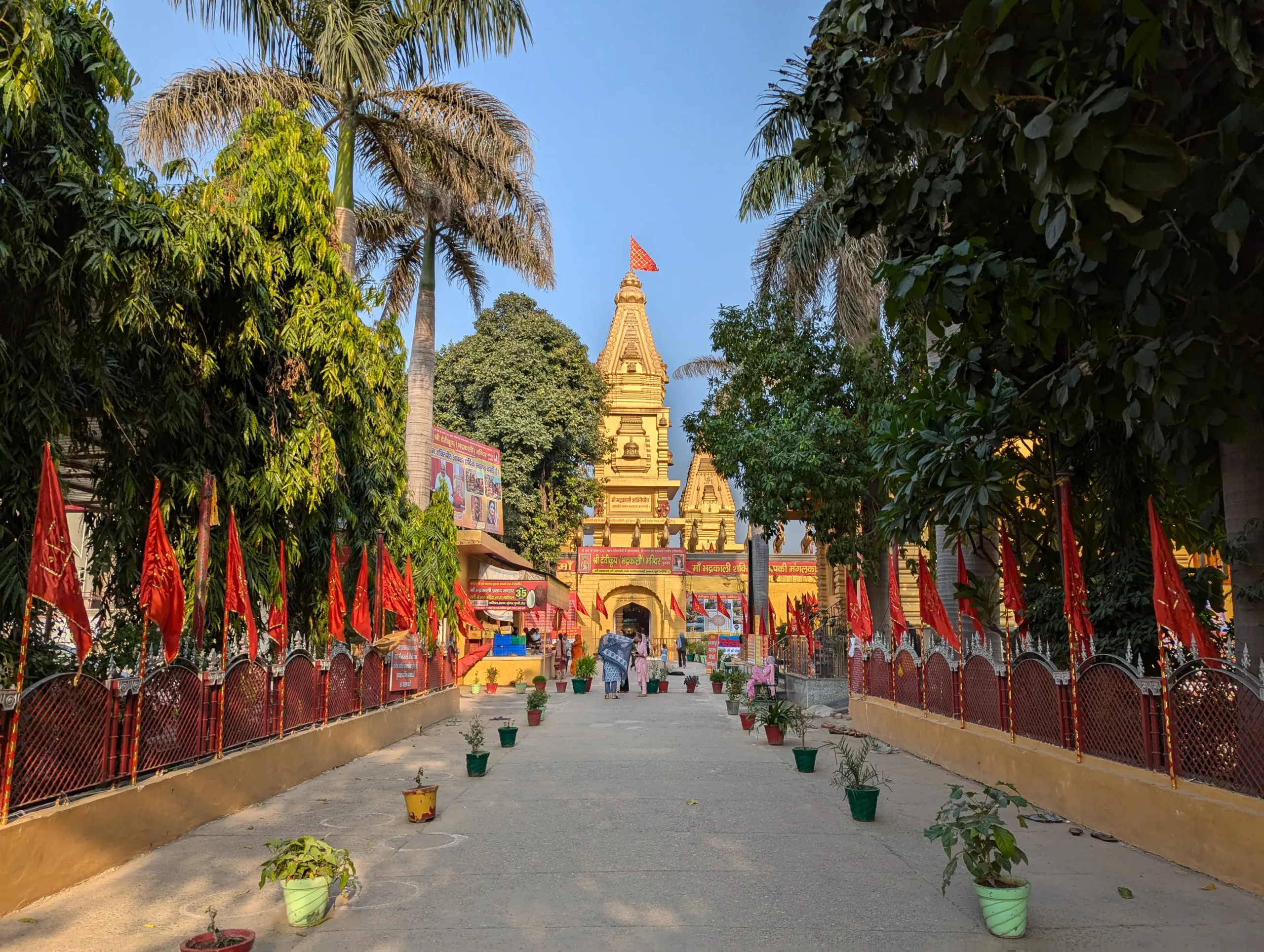 Approach path lined with red flags leading to the shikhara of Devikoop Bhadrakali Shaktipeeth temple in Thanesar, Kurukshetra